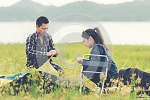 Couple happy helping installingÂ  tent for rest in camping outdoor near river and meadow